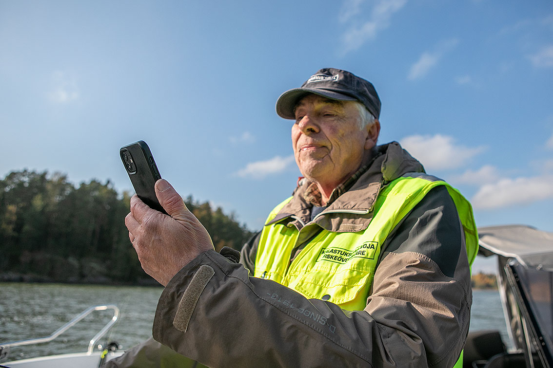Porvoon-Sipoon kalatalousalueen kalastuksenvalvojana toimiva Timo Liljendal tarkastaa kalastajan kalastonhoitomaksun asiakkaan matkapuhelimelta.
