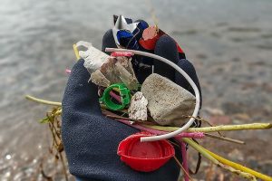 Ihmisen kädessä on meren rannalta kerättyä muoviroskaa.