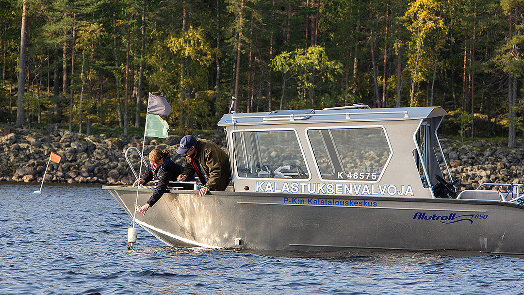 Kalastuksenvalvojat tarkistavat kalanpyydysten merkintöjä valvontaveneestä.